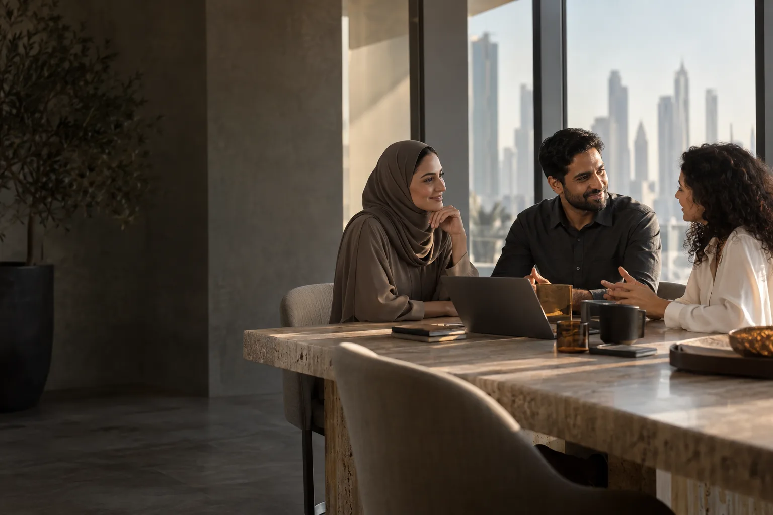 Three colleagues sharing a conversation in a sunlit UAE office